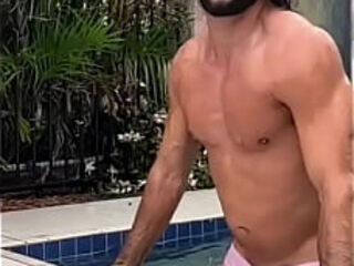 Barbudo tesudo de cabelos longos saindo da piscina com a mala cheia.