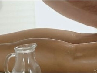 Brunette Lies Face Down While Oil Gets Poured and Rubbed Into Every Curve